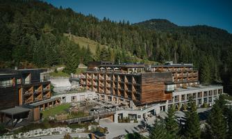A modern hotel area surrounded by lush forests. The architecture combines wood and glass, creating an inviting atmosphere.