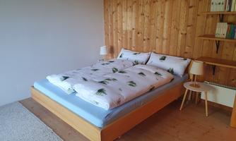 A cozy bedroom with a large double bed and wooden walls.