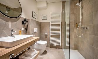 A modern bathroom with a glass shower and a wooden wash basin. The walls are in neutral tones and there is a towel radiator.