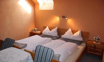 A cozy bedroom with two beds and light ceilings. The room features warm colors and a window that diffuses daylight.