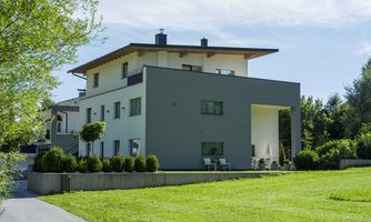 A modern two-story house with an elegant design. The large garden is green and inviting.