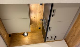 A modern kitchen with gray cabinets and a wooden backsplash. There is a sink and warm lighting.