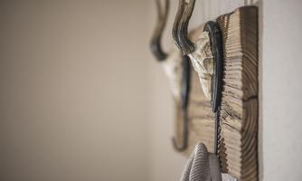 A rustic wall hook with an antler and a decorative piece. The background is designed to be simple and neutral.
