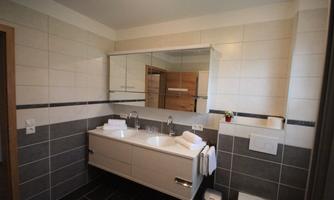 A modern bathroom with large tiles and an elegant vanity. There are fresh towels and a large mirror.