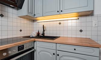 A modern kitchen with bright cabinets and a wooden countertop. The area is well-lit and neatly organized.