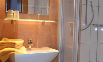 A modern bathroom with a shower and a hand wash basin. Fresh towels are placed on the wash basin.