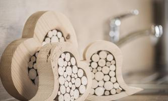 Two decorative wooden hearts filled with small wooden pieces. In the background, a kitchen faucet is visible.