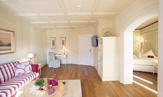 A cozy living space with a red sofa and a table. The room features bright walls and a warm wooden floor.