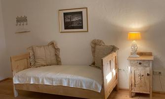 A cozy bedroom with a wooden bed and soft lighting. The walls are bright and the decor is simple and inviting.