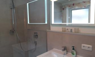 A modern bathroom with a shower and a sink. The lighting creates a bright and inviting atmosphere.