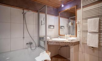A modern bathroom with a bathtub and a shower. The vanity is equipped with toiletries and towels.