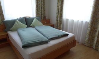 A bright bedroom with a large bed and comfortable pillows. Large windows let in plenty of natural light.