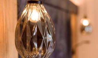 An elegant light bulb in a tasteful lamp socket. The background is softly blurred and showcases warm tones.