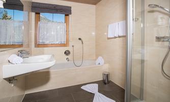 A modern bathroom with a bathtub and a shower. Fresh towels and an elegant design are visible.