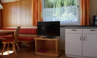 A cozy interior with a seating area and a television. Large windows let in plenty of light.