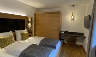 A modern hotel room with a large bed and stylish decor. There is a desk and a television on the wall.