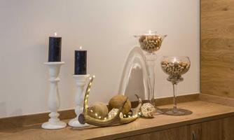 A stylish decoration with white candle holders and dark candles. Vases with decorative elements and a pretty bowl create a cozy atmosphere.