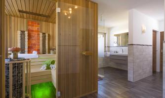 A modern sauna with wooden paneling and a cozy atmosphere. The adjacent bathroom area appears bright and inviting.