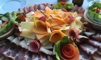A rich platter selection with various types of cheese, cold cuts, and fresh vegetables. The presentation is colorful and attractively decorated.