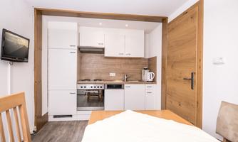 A modern kitchen with white cabinets and wooden accents. The dining area is simply furnished and offers seating for four people.