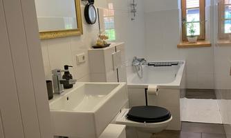 A modern bathroom with a bathtub and a sink. Bright walls and natural light sources create an inviting atmosphere.