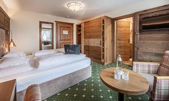 A cozy room with two beds, wood paneling, and modern furniture. A small table with a water bottle and glasses invites you to linger.