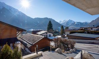 A beautiful alpine landscape with snow-covered mountains and typical wooden buildings. The sun shines brightly over the tranquil surroundings.
