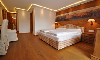 A cozy bedroom with a double bed and wooden furniture. The warm lighting creates an inviting atmosphere.