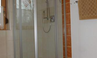 A modern shower cabin made of glass in a bright bathroom. The floor is designed with decorative tiles.