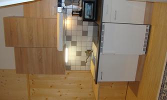 A modern kitchen with wooden furniture and a bright tile backsplash. The equipment includes a stove, a refrigerator, and a sink.