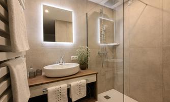 A modern bathroom with a round sink and a large mirror. The glass shower and warm colors create an inviting atmosphere.