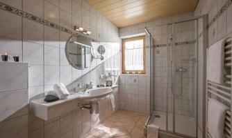 A modern bathroom with a shower and a large washbasin. Bright tiles and natural light sources create an inviting atmosphere.