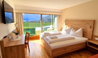 A cozy room with a double bed and beautiful wooden furniture. Large windows offer a great view of the landscape.