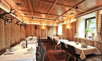 A cozy restaurant with wood paneling and elegant tables. The walls are decorated with antlers, creating a rustic atmosphere.