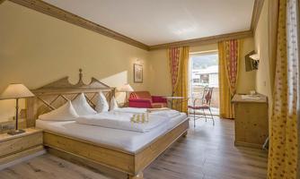 A cozy room with a large bed and modern furniture. The windows let in plenty of daylight and offer a lovely view outside.
