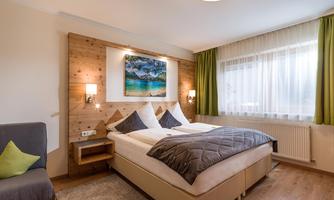 A cozy bedroom with a double bed and wooden paneling. The room is bright and modern, with a beautiful painting on the wall.