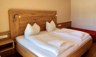 A modern bedroom with a large wooden bed and white bedding. There is a cozy atmosphere with minimal decor.