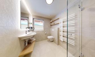 A modern bathroom with a glass shower and an elegant sink. Bright tiles and large windows provide plenty of light.