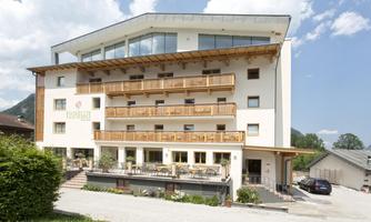 A modern hotel building with several balconies and large windows.  
Surrounded by beautiful scenery and a clear sky.