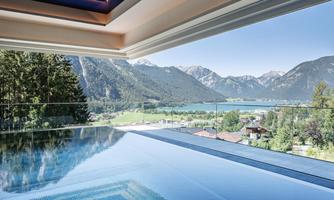 A modern interior with an infinity pool and stunning views of mountains and a lake. The clear view and light create a relaxing atmosphere.