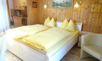 A cozy bedroom with a large bed and yellow pillows. The walls are made of wood, creating a warm atmosphere.