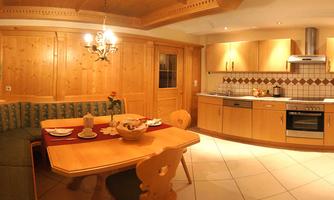 A cozy kitchen and dining corner with wood paneling. The round table is set for a meal, and the furnishings are modern and functional.