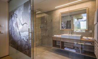 A modern bathroom with a glass shower and an elegant stone sink. The walls are designed with inviting, neutral colors.
