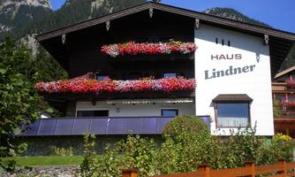 A cozy house with colorful flowers on the balcony. In the background, mountains can be seen that form a beautiful landscape.