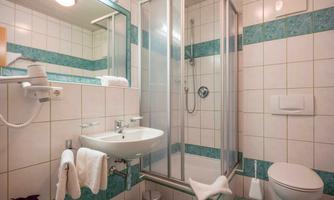 A modern bathroom with a shower, a sink, and a toilet. The walls are brightly tiled, with blue accents.