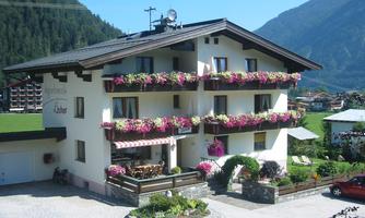 A charming house with blooming balconies and a well-maintained garden. The surroundings are picturesque, surrounded by mountains and a tranquil landscape.