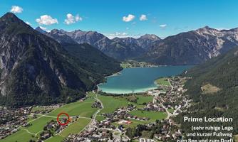 A picturesque landscape with mountains and a clear lake. In the foreground, there is a small village with green meadows.