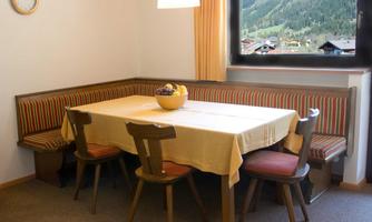 A cozy dining area with a table and chairs. Through the window, you can see a beautiful mountain landscape.