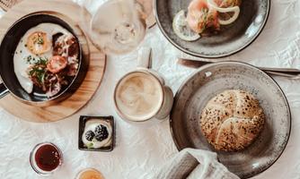 A hearty breakfast with fried eggs, salmon, and fresh bread. Accompanied by coffee specialties and various juices set on a pretty table.