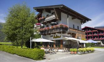 A cozy café with a large balcony and blooming plants. The surroundings are green and inviting, perfect for a relaxing stay.